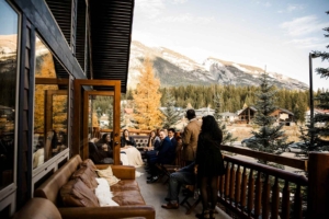 Wedding guests on the balcony at A Bear and Bison Inn with golden larch trees in the background.